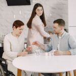 Opiekunka podaje leki starszej kobiecie na wózku w nowoczesnej kuchni