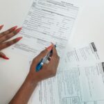 Kobieta o czerwonych paznokciach wypełnia formularz przy biurku
