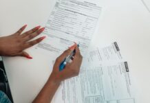 Kobieta o czerwonych paznokciach wypełnia formularz przy biurku