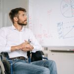 Mężczyzna na wózku inwalidzkim analizuje wykresy na tablicy w biurze